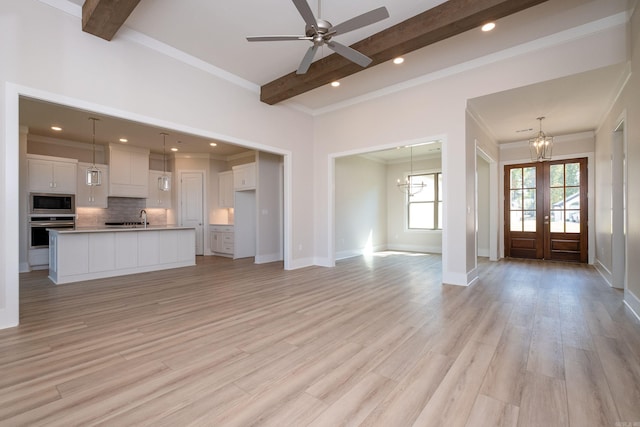 unfurnished living room with a sink, baseboards, french doors, light wood-type flooring, and beam ceiling