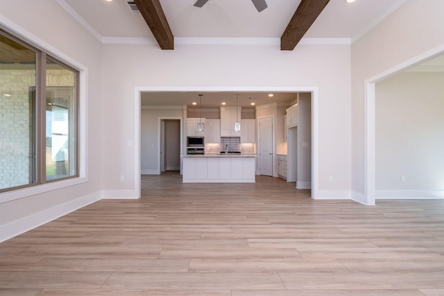 unfurnished living room with beamed ceiling, light wood-style flooring, and baseboards