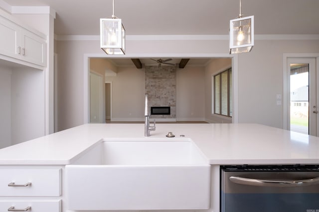 kitchen with light countertops, a fireplace, decorative light fixtures, and stainless steel dishwasher