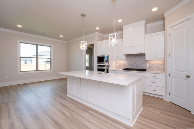 kitchen featuring light countertops, appliances with stainless steel finishes, a kitchen island with sink, and white cabinets