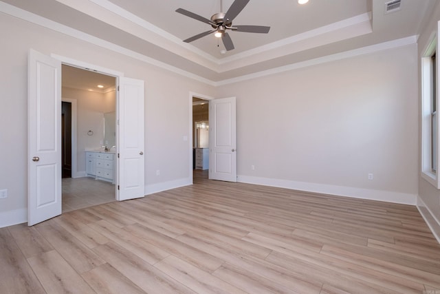 interior space featuring a tray ceiling, light wood-style flooring, and baseboards