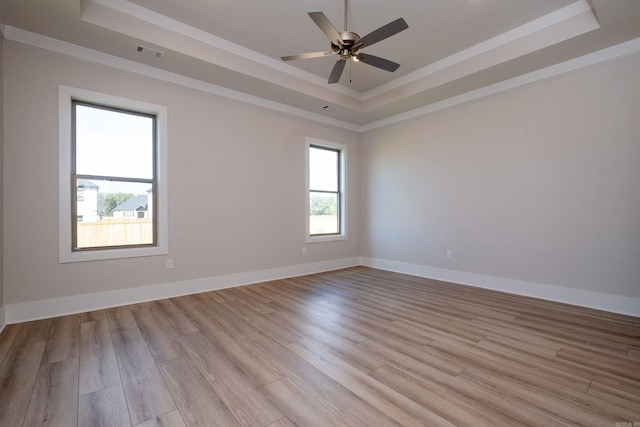 spare room featuring light wood finished floors, visible vents, baseboards, ceiling fan, and a tray ceiling