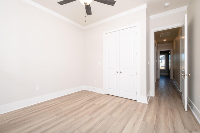 unfurnished bedroom with a ceiling fan, baseboards, a closet, light wood finished floors, and crown molding