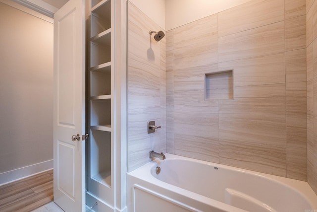 full bath featuring wood finished floors, bathtub / shower combination, and baseboards