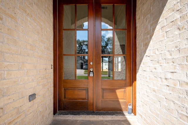 view of exterior entry featuring brick siding and french doors