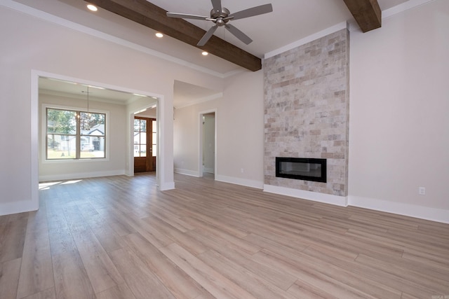 unfurnished living room featuring a large fireplace, baseboards, beamed ceiling, and light wood finished floors