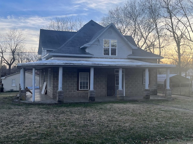 view of front of home with a porch, a yard, and a shingled roof