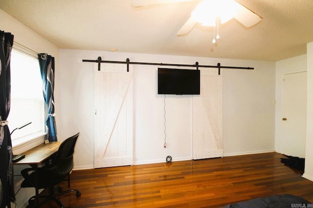 unfurnished office featuring dark wood-style floors, a textured ceiling, and a barn door