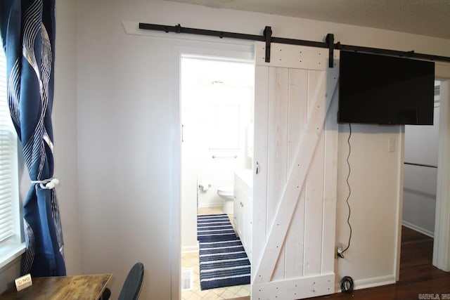 interior space featuring a barn door, ensuite bath, visible vents, and baseboards