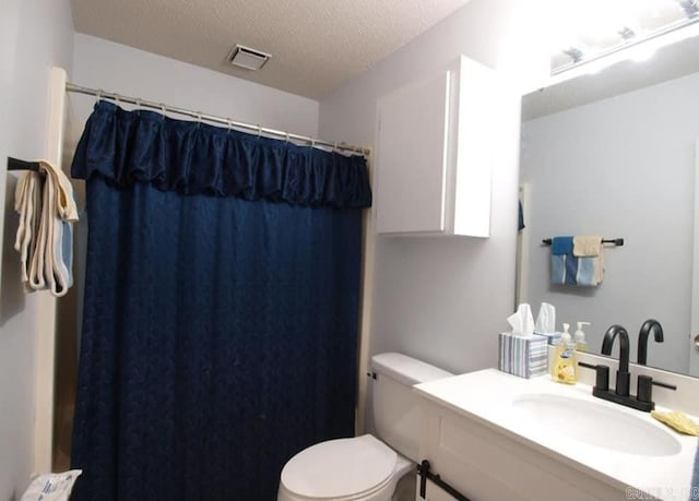 bathroom featuring curtained shower, visible vents, toilet, vanity, and a textured ceiling