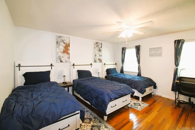 bedroom featuring a ceiling fan, dark wood-style flooring, and a textured ceiling