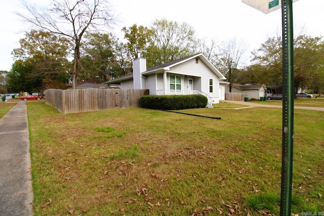 view of side of home with a chimney, fence, and a lawn