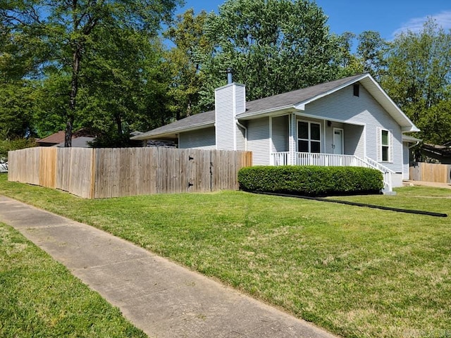 view of side of property featuring a chimney, fence, a porch, and a lawn