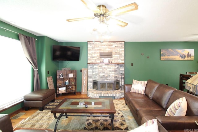 living room featuring ceiling fan, a fireplace, wood finished floors, and visible vents