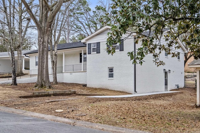 view of side of property with a porch and brick siding