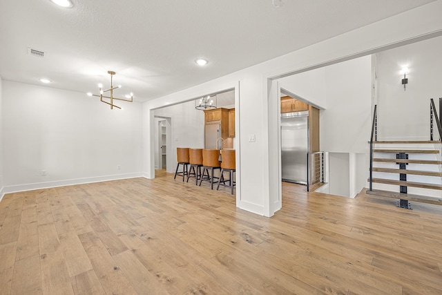 interior space with visible vents, stairway, a chandelier, and light wood-style flooring