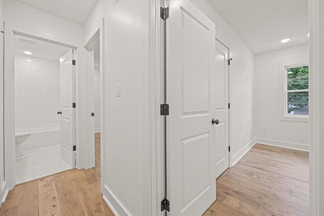 corridor with light wood-style floors and baseboards