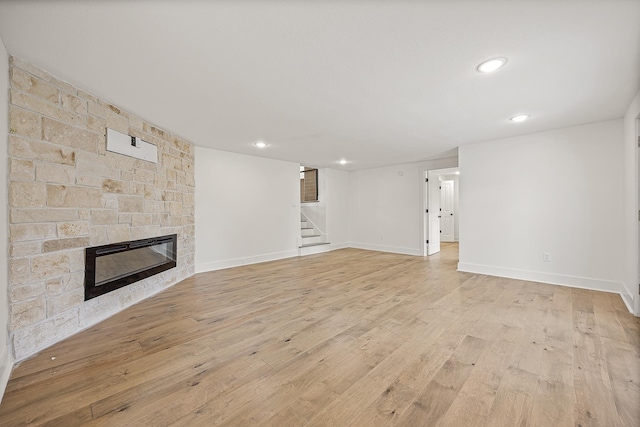 unfurnished living room featuring recessed lighting, a fireplace, baseboards, light wood-style floors, and stairway