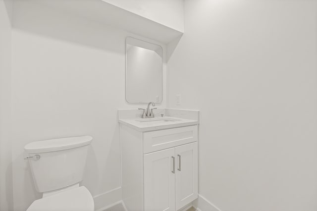 bathroom featuring toilet, baseboards, and vanity