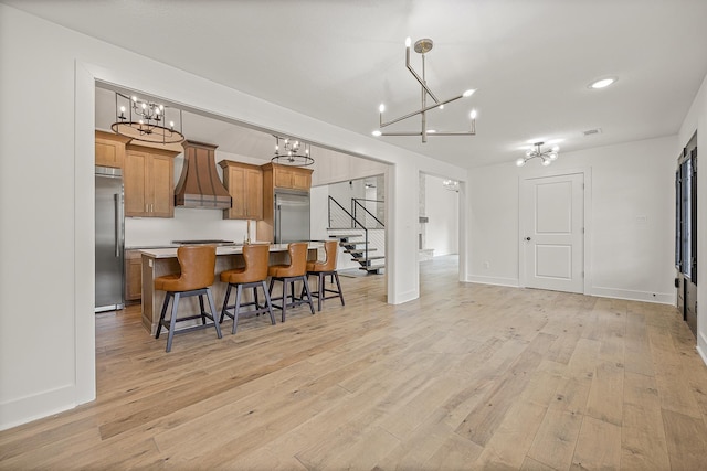 kitchen featuring brown cabinets, light countertops, a kitchen island, premium range hood, and built in refrigerator