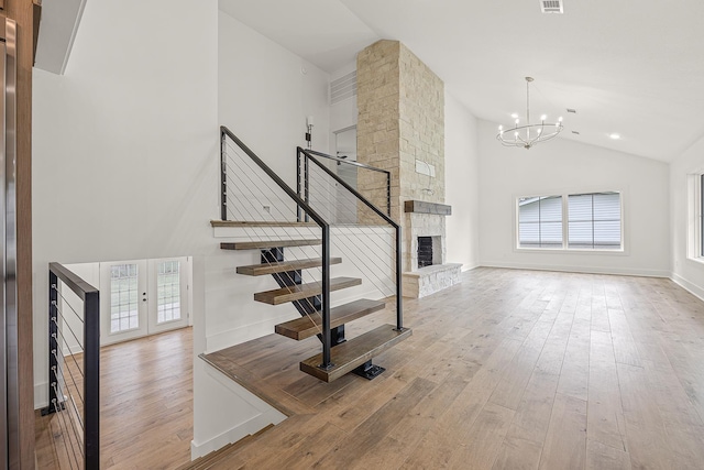 interior space featuring high vaulted ceiling, a fireplace, wood finished floors, and visible vents