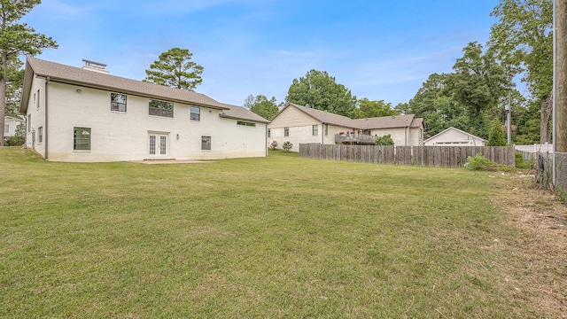 rear view of property featuring a yard and fence