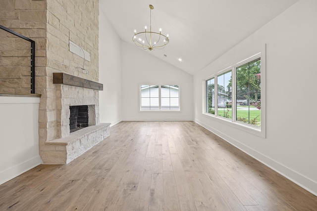 unfurnished living room with an inviting chandelier, a fireplace, high vaulted ceiling, and wood finished floors