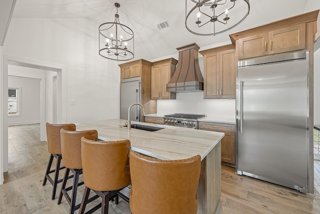 kitchen with visible vents, high quality appliances, light wood-style floors, pendant lighting, and a sink