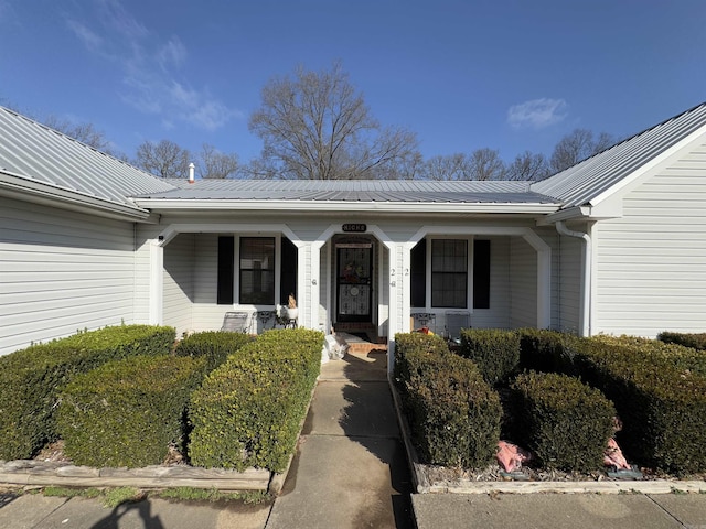 doorway to property with a porch and metal roof