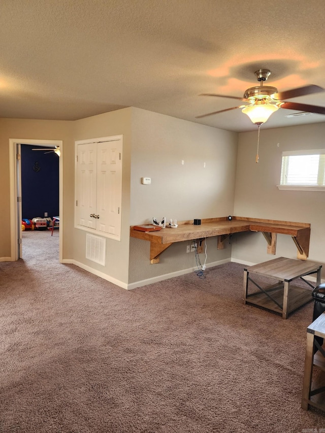 unfurnished office with baseboards, visible vents, a ceiling fan, carpet, and a textured ceiling