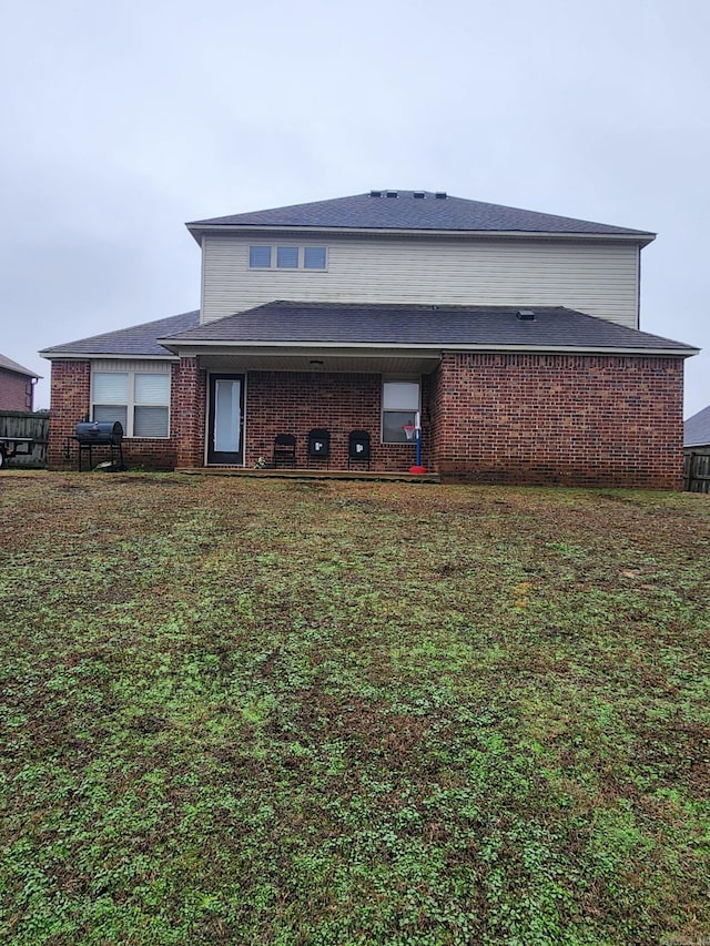 rear view of property with a yard and brick siding