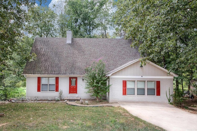 view of front facade featuring a shingled roof, brick siding, a chimney, and a front lawn