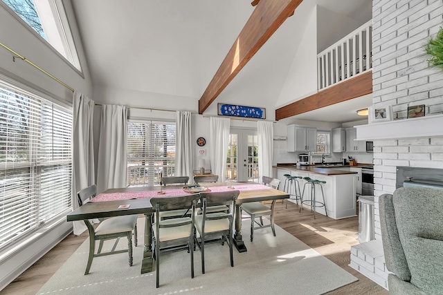 dining space with high vaulted ceiling, light wood-type flooring, french doors, and beamed ceiling