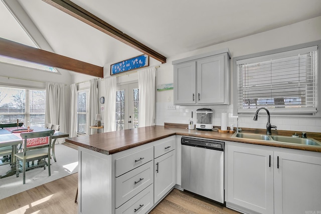 kitchen with white cabinetry, dishwasher, a peninsula, and a sink