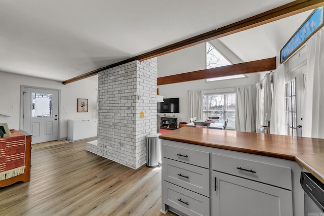 kitchen with dishwasher, a healthy amount of sunlight, lofted ceiling with beams, open floor plan, and light wood-type flooring