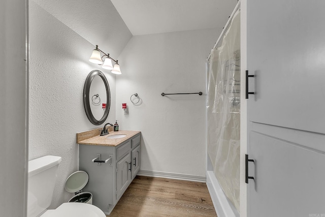 full bathroom featuring a textured wall, toilet, wood finished floors, vanity, and baseboards