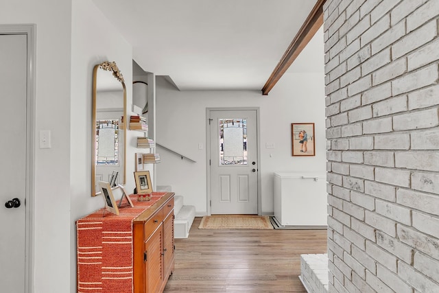 foyer entrance featuring brick wall, stairway, light wood-type flooring, and baseboards