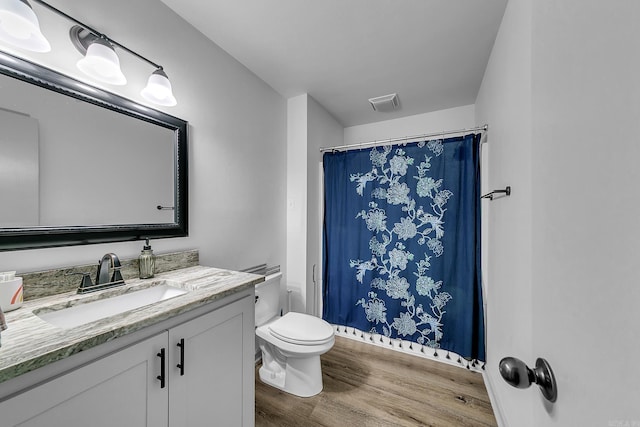 full bath with toilet, visible vents, wood finished floors, and vanity