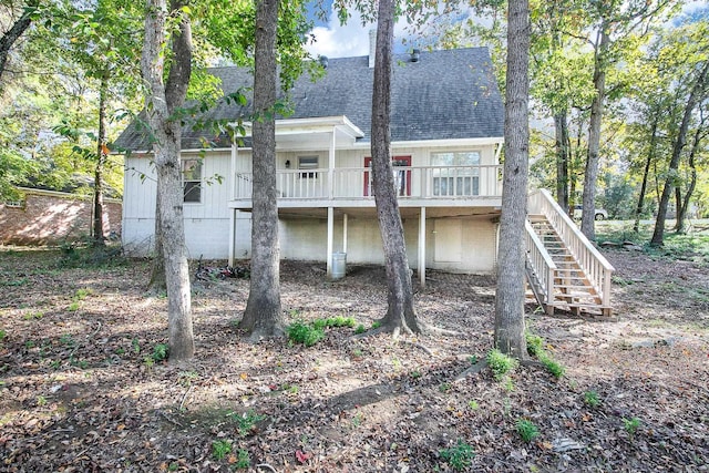 rear view of house with a shingled roof, a deck, and stairs