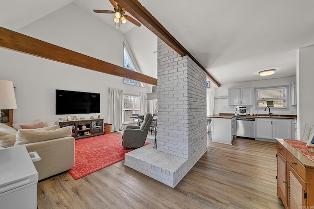 living room with ceiling fan, high vaulted ceiling, light wood finished floors, and beamed ceiling