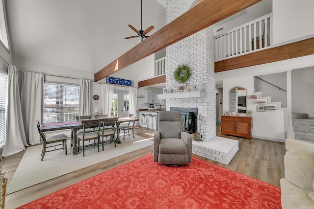 living area with a fireplace, light wood finished floors, a high ceiling, and stairs