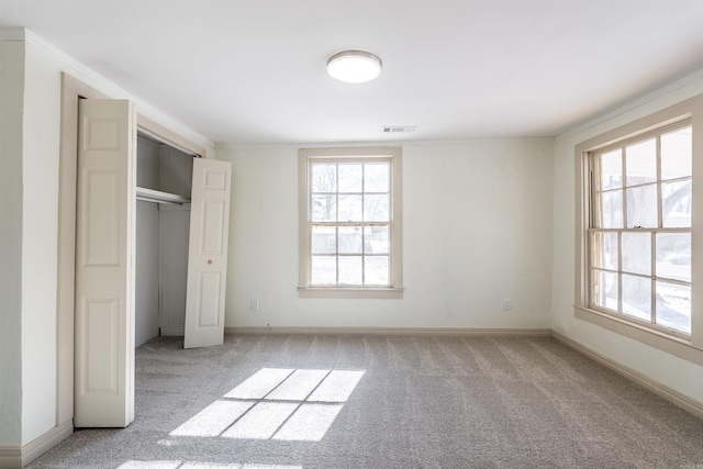 unfurnished bedroom with multiple windows, visible vents, and light colored carpet