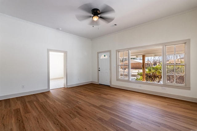 empty room with baseboards, visible vents, ceiling fan, ornamental molding, and wood finished floors