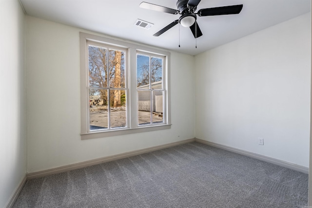 carpeted spare room featuring ceiling fan, visible vents, and baseboards