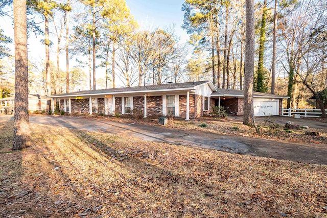 ranch-style home featuring an attached garage, aphalt driveway, and brick siding