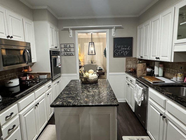 kitchen featuring appliances with stainless steel finishes, glass insert cabinets, white cabinetry, and a center island