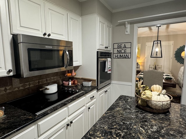 kitchen featuring crown molding, appliances with stainless steel finishes, white cabinetry, and decorative light fixtures