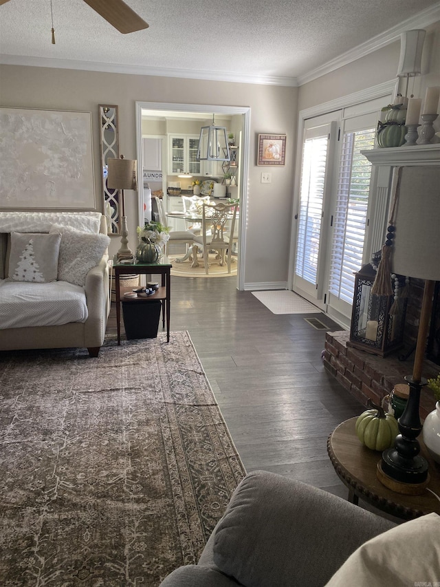 living area featuring a textured ceiling, a ceiling fan, dark wood finished floors, and crown molding