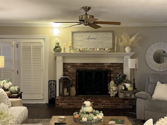 living room featuring a brick fireplace, ornamental molding, dark wood finished floors, and a textured ceiling