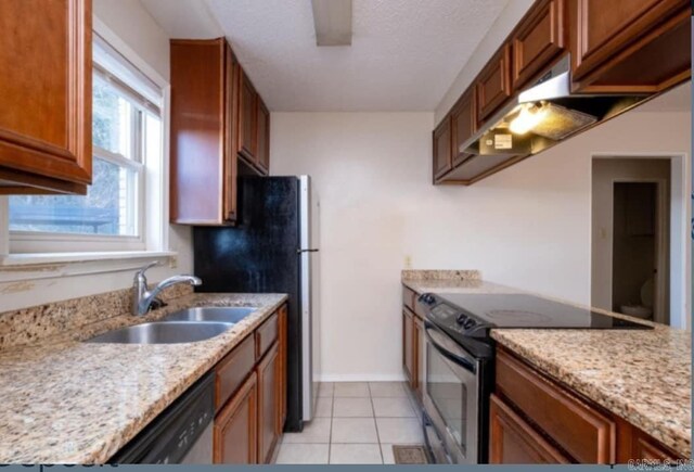 kitchen with light stone counters, electric stove, light tile patterned floors, brown cabinetry, and a sink
